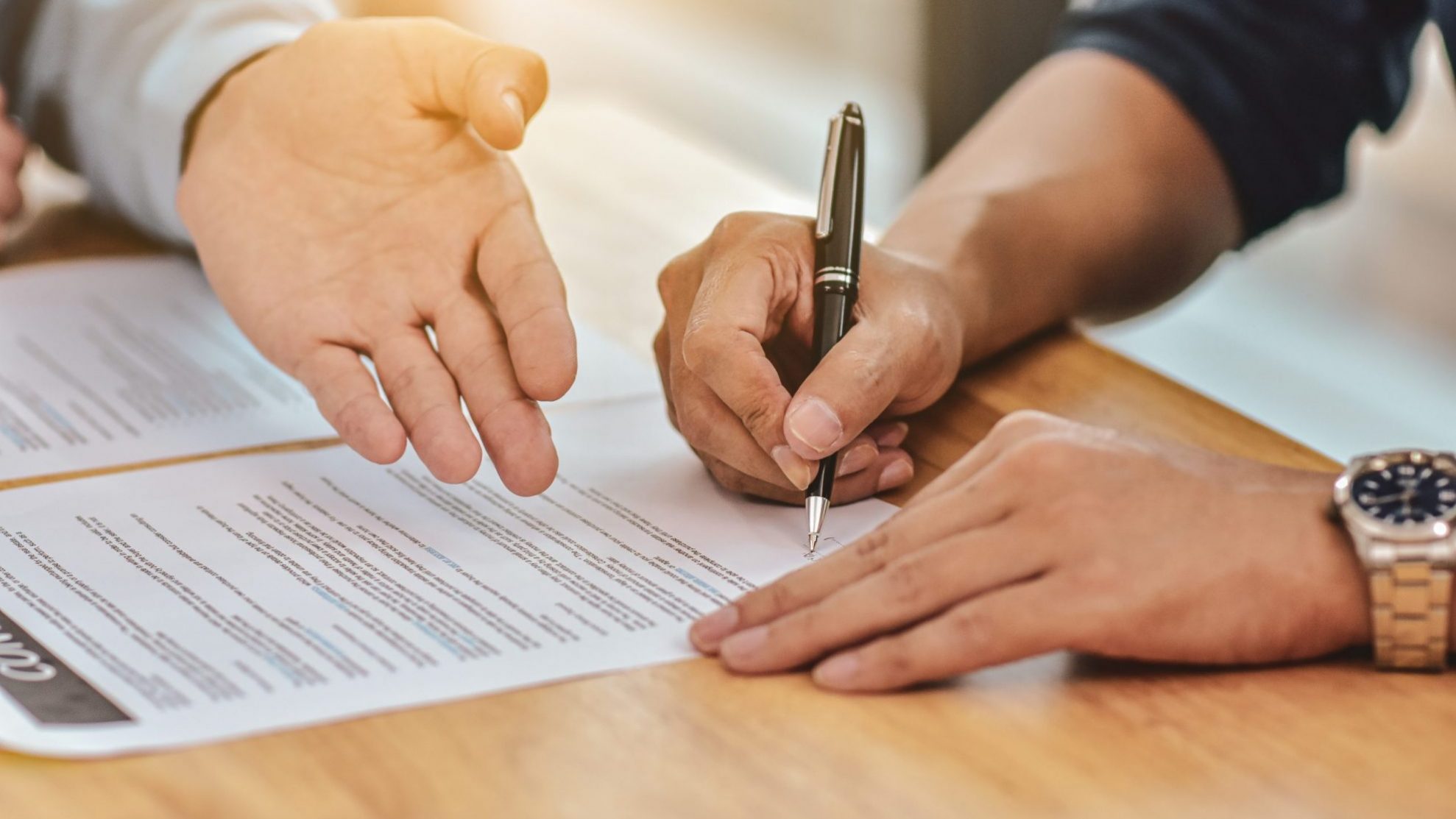 Photo of person signing contract illustrates blog: "Commercial Real Estate: What Is an “As-Is” Clause?"