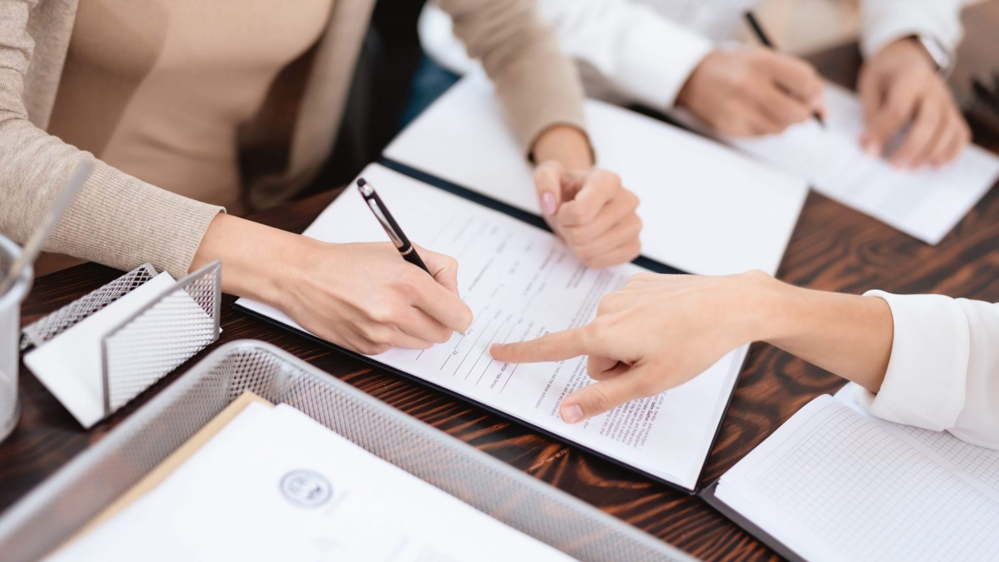 Photo of woman signing documents illustrates blog "What Is a Triple Net Lease?"