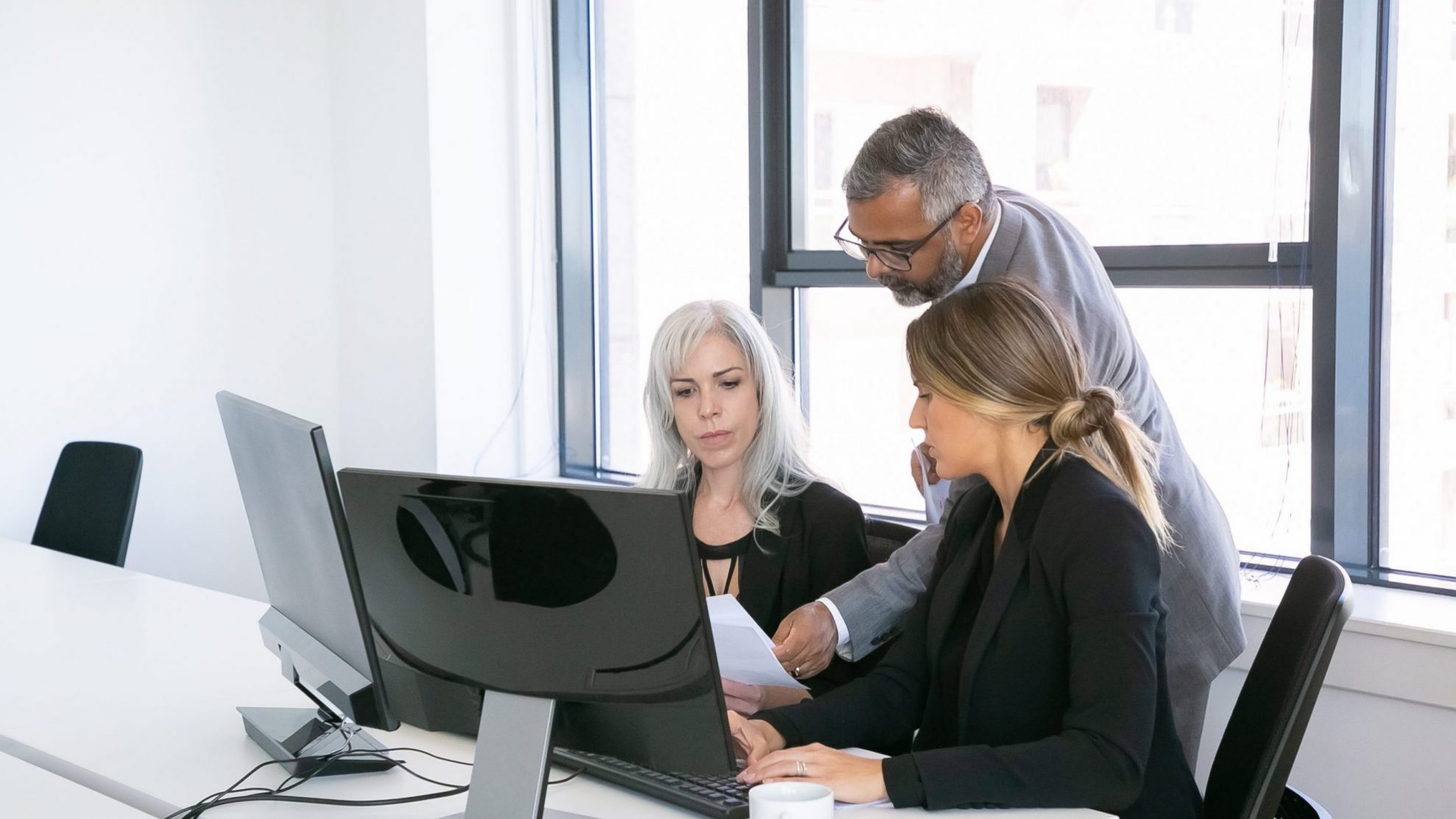 Photo of two women and a man looking at documents illustrates blog "Are CAM Charges Negotiable?"