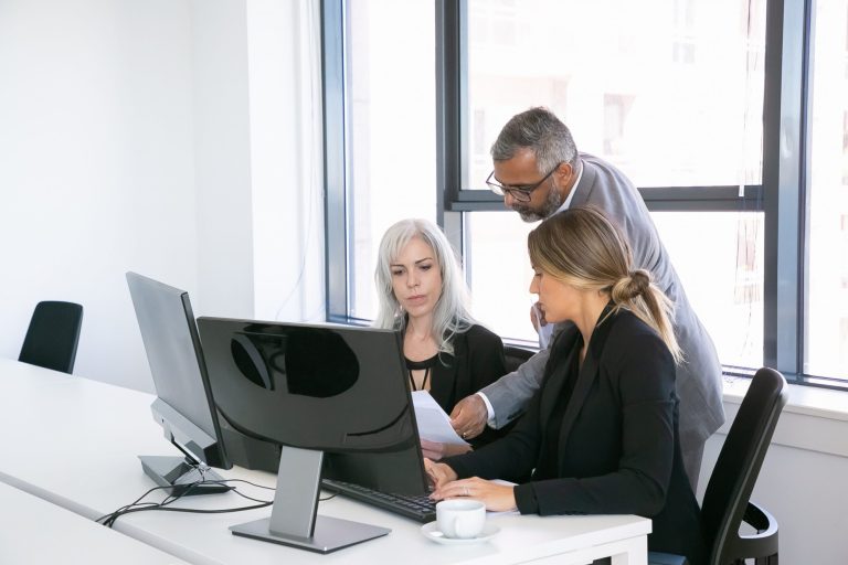 Photo of two women and a man looking at documents illustrates blog "Are CAM Charges Negotiable?"