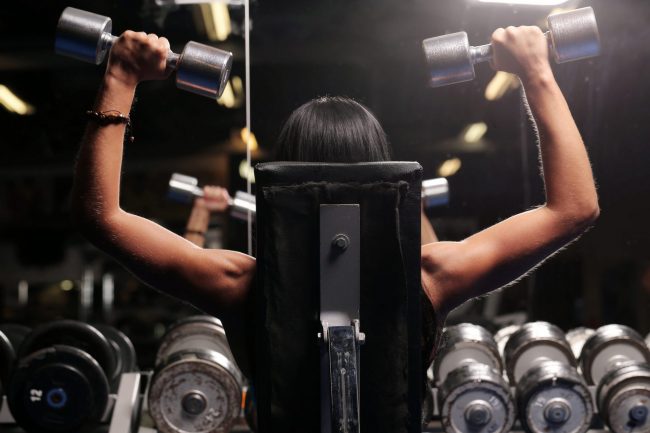 Muscular beautiful woman at a gym Photo of woman exercising with dumbbells illustrates blog: "Gyms Become Popular Tenants in the Post-Pandemic World"