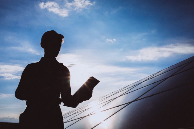 Photo of worker by solar panel illustrates blog: "What Is a Sustainable Warehouse?"
